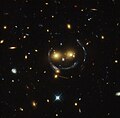 "Smiley" image of galaxy cluster (SDSS J1038+4849) & gravitational lensing (an Einstein ring) (HST).[58]